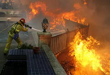Firefighter spraying flames with hose