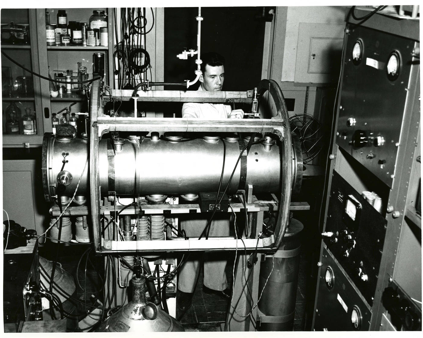 Man standing behind a big horizontal cylinder of metal and a lot of wires