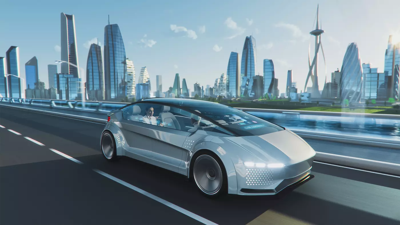 People sit facing each other in a silver driverless car moving through a futuristic cityscape.