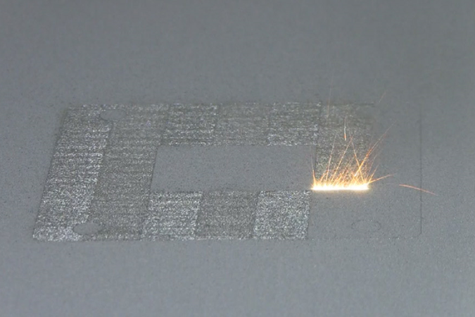A high-power laser spot scans back and forth over a layer of cobalt-chrome powder on NIST's powder bed fusion additive manufacturing machine. Where it touches, the powder melts and fuses to underlying layers until a fully dense 3D metal part is formed. The laser travels back and forth so fast that, in this still image frame, it appears to form a white hot stripe about 10 millimeters wide.