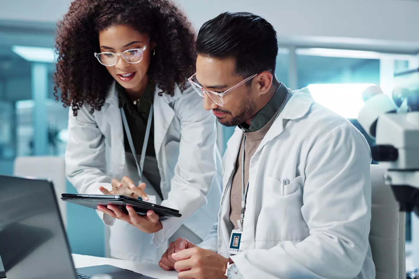 two researchers, working in a lab, happily collaborate at a computer 