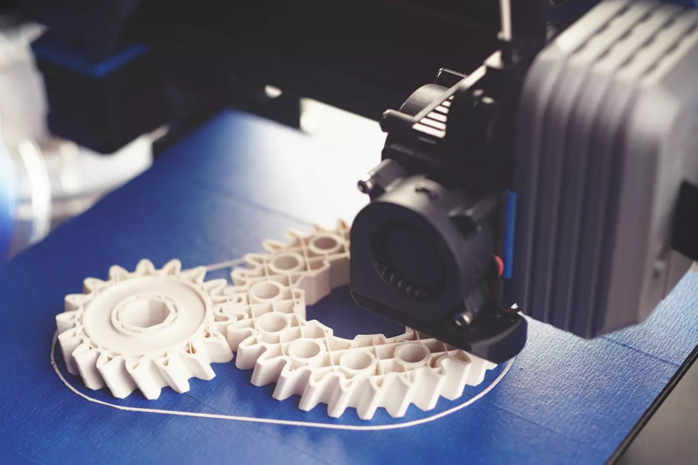 a 3D printer prints white gears using polymer filament