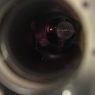 View through a circular opening into a dark interior. A red dot floats in the darkness. 