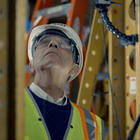 Photo of structural elements surrounding man with helmet and glasses looking up 