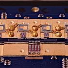 Circuit board with various square chips and gold screws. Small letters in the center say: NIST True Bq.