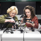 Angie Hight Walker and Amber McCreary stand side by side in the lab adjusting a complex scientific device.