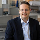 Andrew Regenscheid poses sitting at a table in the NIST library. 