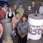 A group of people around a cylindrical time capsule