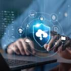 Illustration shows cloud, cybersecurity and identity icons floating over an open laptop with a person's hands at the keyboard.