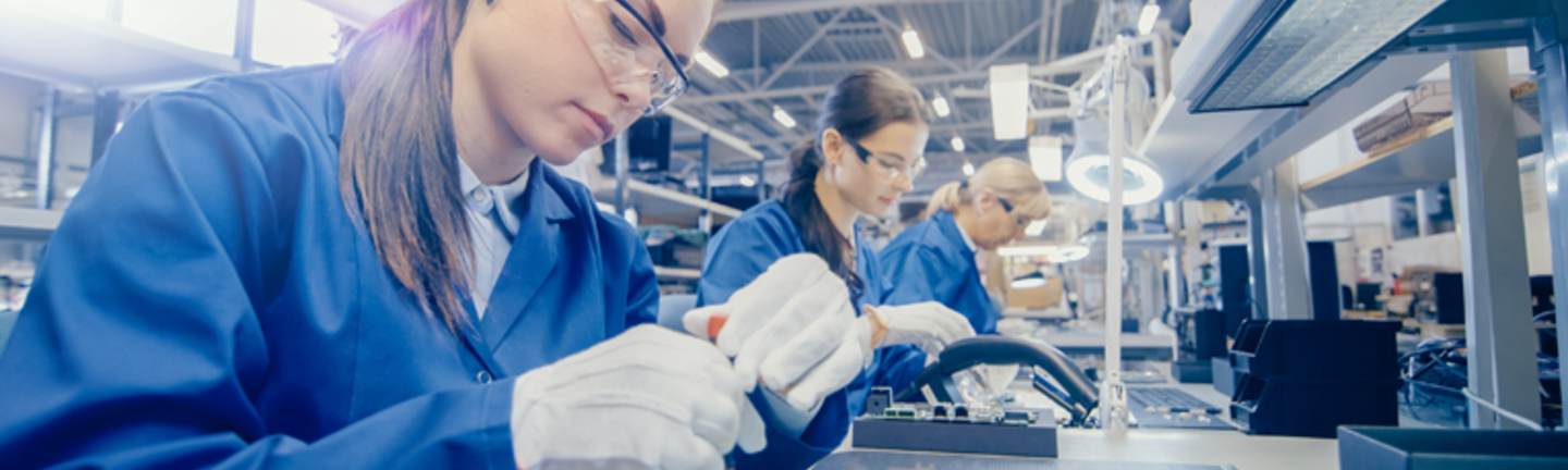 emale Electronics Factory Worker in Blue Work Coat and Protective Glasses