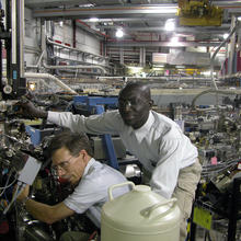 NIST materials scientists Cherno Jaye (r.) and Dan Fischer adjust a sample chamber for NIST's soft x-ray materials characterization beamline at the National Synchrotron Light Source.