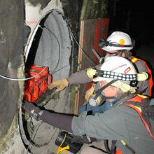 NIST electrical engineers Chris Holloway and Galen Koepke place transmitters in a protected air vent at the old Washington Convention Center prior to the implosion of the building.