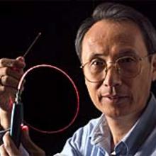 Xiao Tang of NIST's Information Technology Laboratory holding up an optical fiber channel