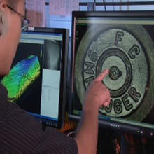 NIST engineer pointing at a firing pin impression.