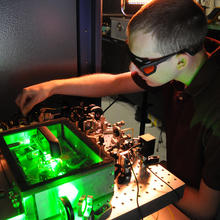 Photo of UC graduate student Matt Kirchner fine-tuning an ultra-stable microwave generator at NIST