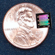 NIST's superconducting circuit containing a 'micro drum' sitting atop of a penny to show how much smaller it is.