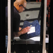 NIST engineering technician Nathaniel Waters examines a bullet-resistant vest being tested