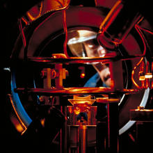 Researcher Kris Helmerson observes a tiny glowing cloud of sodium atoms caught by six intersecting laser beams in a vacuum chamber. 