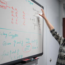 Mathematician Lily Chen standing in front of a white board covered in equations