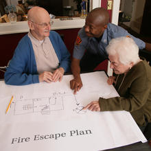 Three people looking at drawing of Fire Escape Plan