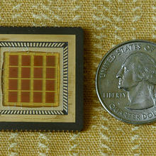A glass microchip next to a quarter showing that the two are approximately the same size