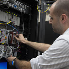 Timothy Zimmerman checking connections in the Cybersecurity for Smart Manufacturing Systems testbed