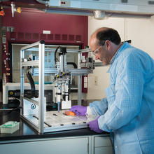 Researcher John Elliott in the lab loading samples into automated liquid handling instrument.