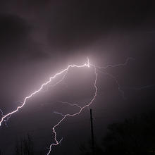 Photo of purplish black sky with a streak of bright lightning