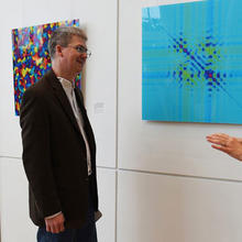 Woman and man talking beside wall with several square illustrations of science art