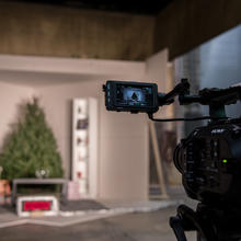 Video camera aimed at a room with a Christmas tree, bookshelf, coffee table and chair
