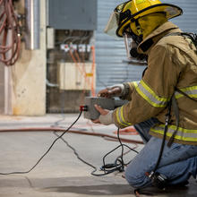 NIST scientist pushes a button to ignite the dry Christmas tree