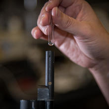 hand holding small glass container dripping simulant into detector