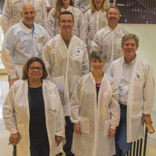 A group of student judges grouped on a flight of stairs wearing white lab coats