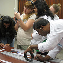 4 teachers stand around a desk working on a project.