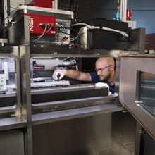 Researcher Brandon Lane making adjustments inside the large 3D printer