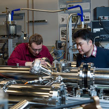 Two men work on a microscope