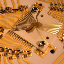 Square device surrounded by a design of gold wiring.