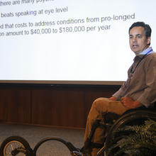 Man in a wheelchair presenting at a conference