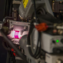 A ruby colored rod, wrapped in tissue paper and illuminated by a bright light, mounted inside an X-ray diffraction machine