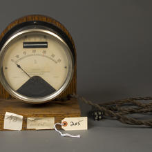 A wood-framed circular face with a line gauge reading from 0 to 35 in 1/2 increments with a red line at 25. Another gauge above goes from 23 to 27, also with a red line at 25. Words read "cycles," Hartmann-Kempf’s Patent" and James G. Biddle Philadelphia.