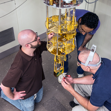 Three men hover around a piece of equipment