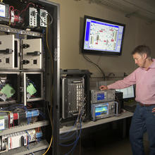NIST engineer Rick Candell is seen monitoring the strength and clarity of a wireless signal run through a virtual factory environment (a graphic of which is seen on a monitor above Candell's head).