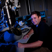 Ryan M. White sitting next to a microscope