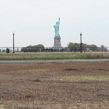 Picture of dirt field with the Statue of Liberty in the background.