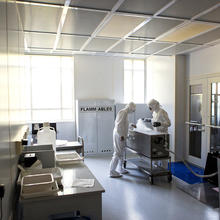 Two scientists wearing hooded suits, gloves and safety goggles work together to prepare samples for long term storage.