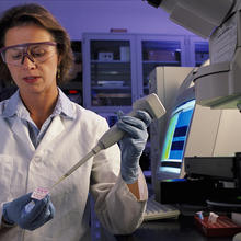NIST biomedical engineer Laurie Locascio places a water sample on a highly sensitive, inexpensive "lab-on-a-chip"