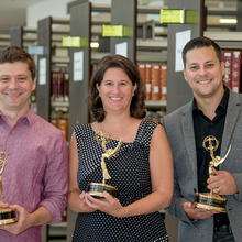 three people hold Emmy Awards in the NIST library