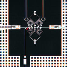 a schematic of an artificial atom. A red arrow to the bottom left points at a Josephson junction that serves as a quantum bit, or qubit.