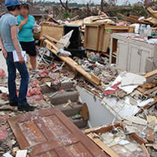 Two people standing among the destruction in Joplin