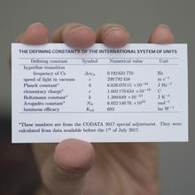 Person holding wallet card showing the values of fundamental constants being used for revising the International System of Units, the modern metric system.